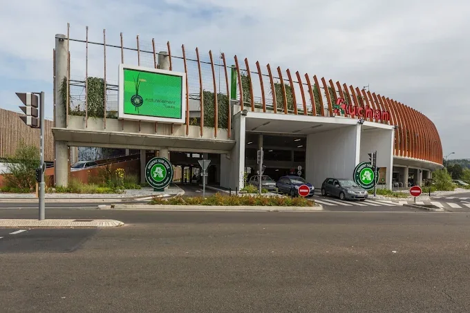 Vue de l’accès au parking du centre commercial Auchan à Nogent-sur-Oise, avec son enseigne rouge